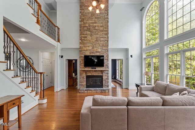 living room featuring a healthy amount of sunlight, a high ceiling, hardwood / wood-style floors, and crown molding