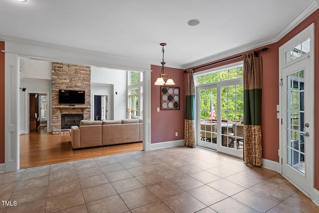 unfurnished living room featuring light hardwood / wood-style floors, crown molding, a stone fireplace, and an inviting chandelier