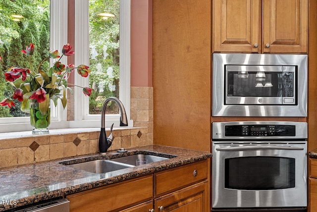 kitchen with dark stone counters, sink, stainless steel appliances, and tasteful backsplash