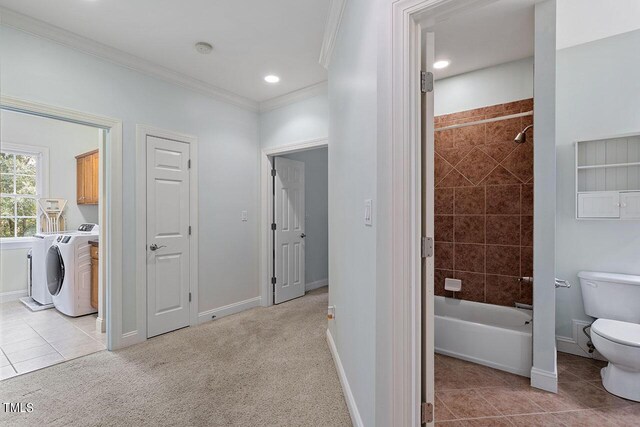 hall with washing machine and dryer, ornamental molding, and light carpet