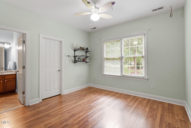 bedroom with light wood-type flooring, ensuite bath, and ceiling fan