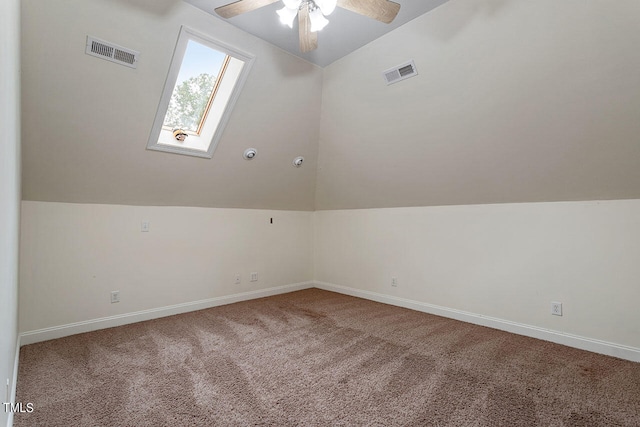 additional living space with vaulted ceiling with skylight, carpet flooring, and ceiling fan