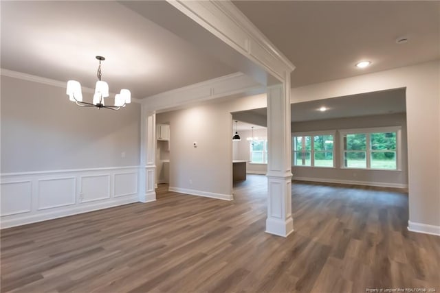 unfurnished room with a notable chandelier, dark hardwood / wood-style flooring, ornamental molding, and decorative columns