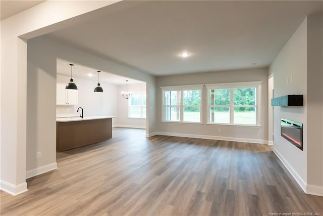 unfurnished living room featuring dark hardwood / wood-style floors, a wealth of natural light, a notable chandelier, and sink