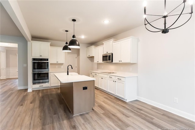 kitchen featuring a center island with sink, white cabinetry, stainless steel appliances, and light hardwood / wood-style flooring