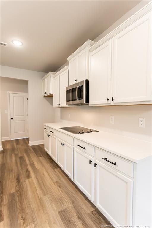 kitchen with white cabinetry, black electric stovetop, and light wood-type flooring