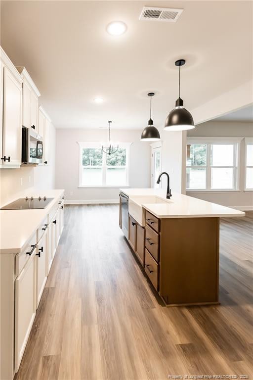 kitchen featuring stainless steel appliances, a kitchen island with sink, sink, white cabinets, and plenty of natural light