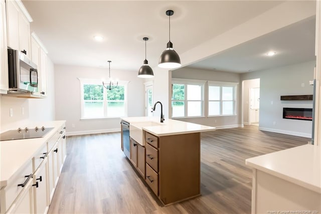 kitchen with white cabinets, dark hardwood / wood-style flooring, stainless steel appliances, and a kitchen island with sink