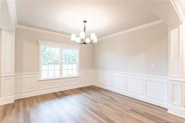 unfurnished room with crown molding, light hardwood / wood-style flooring, and a notable chandelier