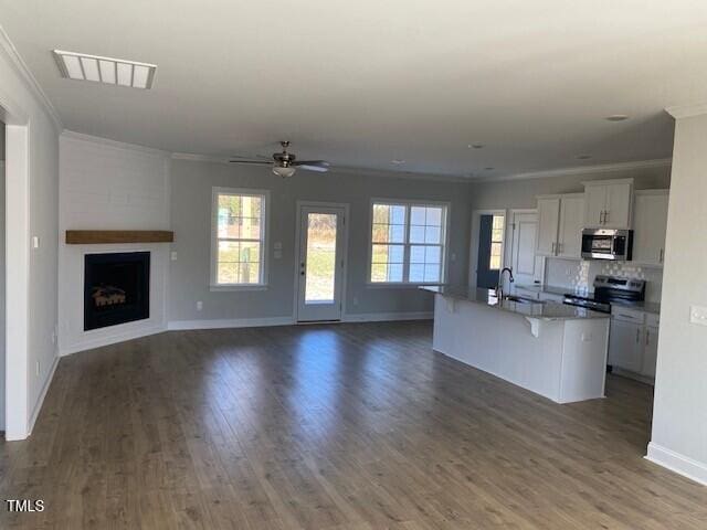 kitchen featuring white cabinetry, a kitchen bar, appliances with stainless steel finishes, and a center island with sink