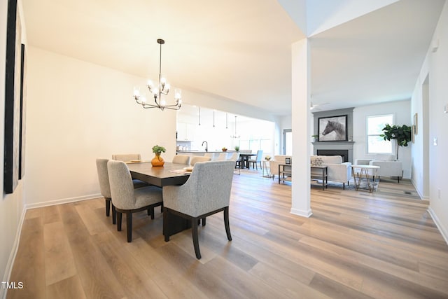 dining space featuring sink, ceiling fan with notable chandelier, and light wood-type flooring