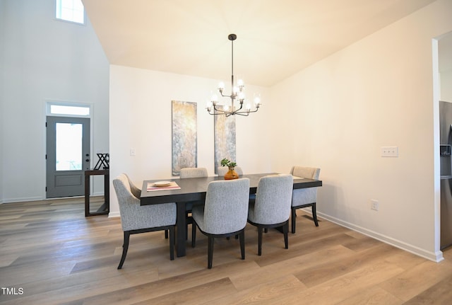 dining room with wood-type flooring, a towering ceiling, and a chandelier