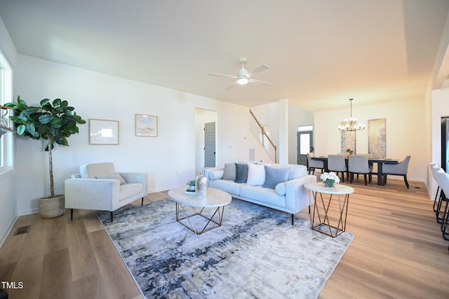 living room featuring ceiling fan with notable chandelier, a healthy amount of sunlight, and light hardwood / wood-style floors