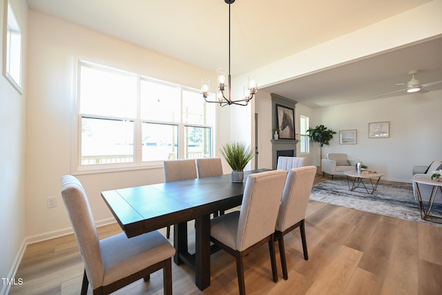 dining space with ceiling fan with notable chandelier and light hardwood / wood-style floors