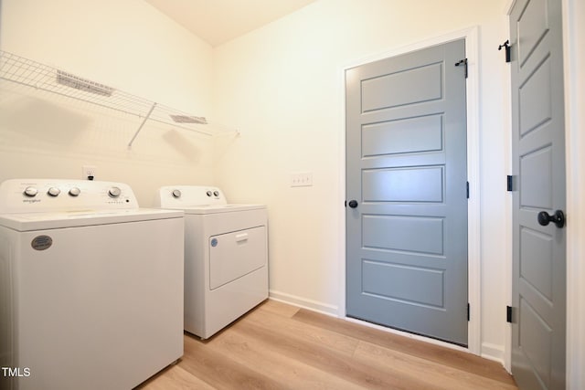 washroom featuring washing machine and dryer and light hardwood / wood-style floors