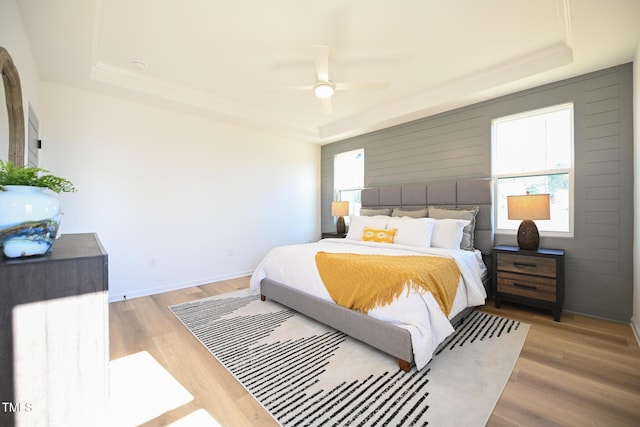 bedroom featuring hardwood / wood-style flooring, a raised ceiling, and ceiling fan