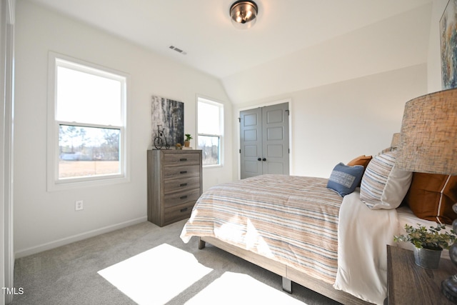 bedroom featuring lofted ceiling, light colored carpet, and a closet