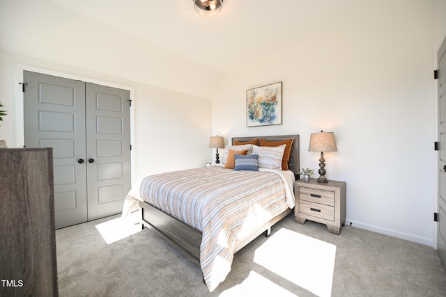 bedroom with light colored carpet, vaulted ceiling, and a closet