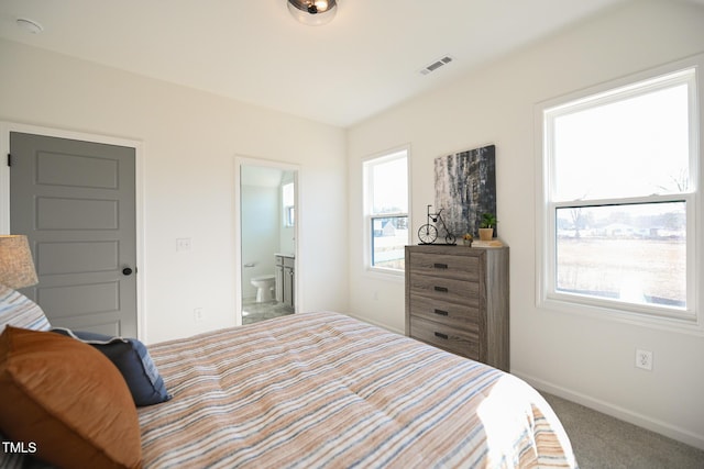 carpeted bedroom featuring multiple windows and connected bathroom