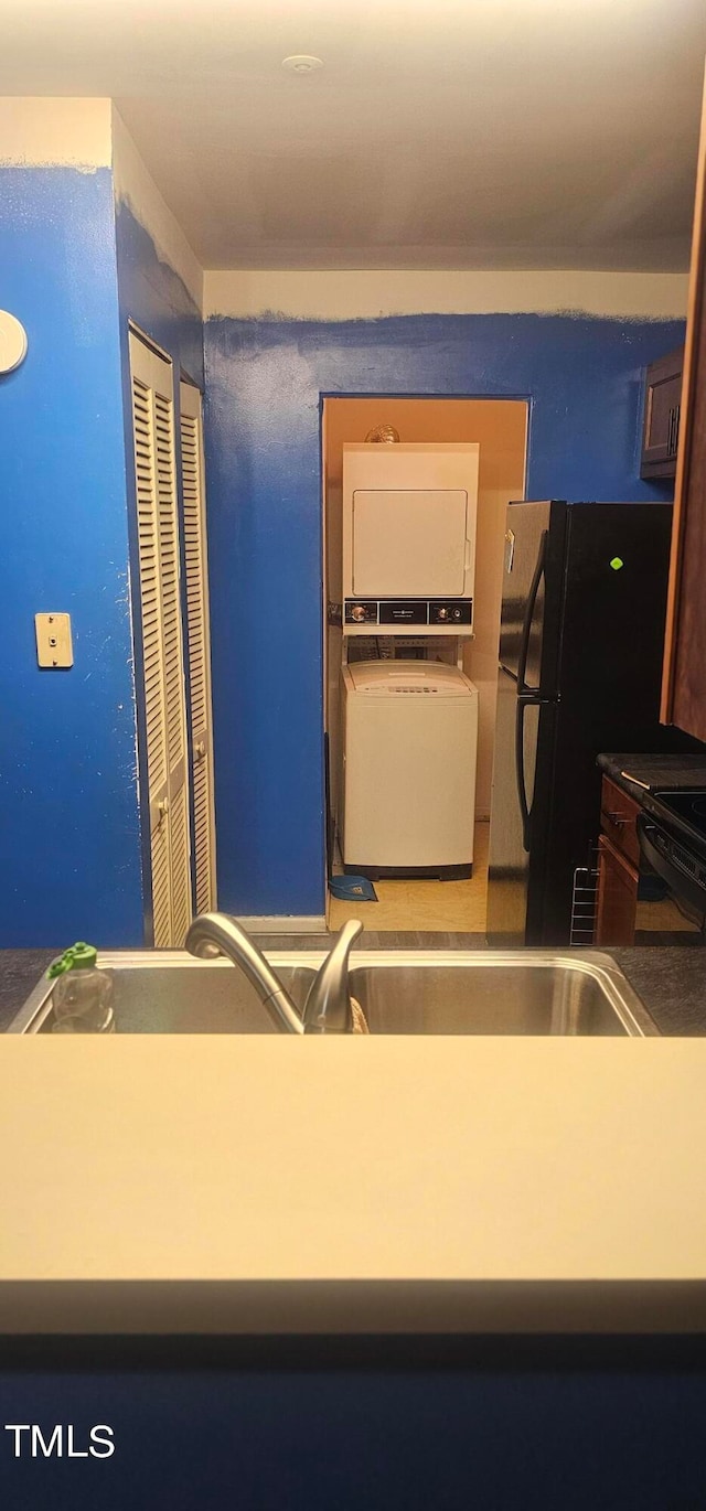 interior space featuring black appliances and stacked washer / drying machine