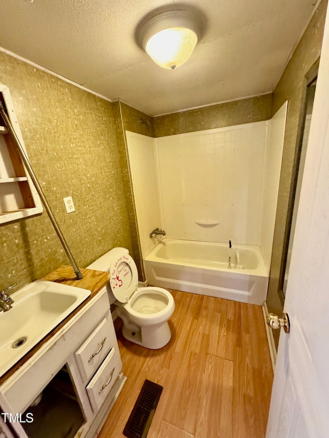 full bathroom featuring shower / washtub combination, a textured ceiling, wood-type flooring, toilet, and vanity