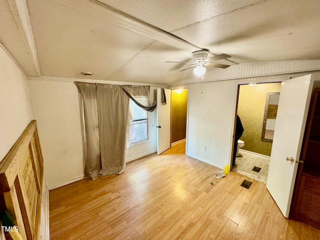 unfurnished bedroom featuring lofted ceiling, wood-type flooring, a textured ceiling, ensuite bathroom, and ceiling fan