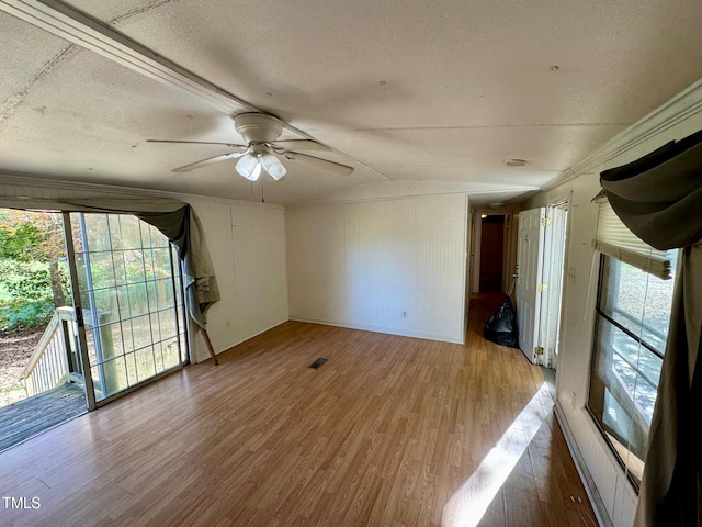 spare room with lofted ceiling, ceiling fan, a textured ceiling, hardwood / wood-style flooring, and wooden walls