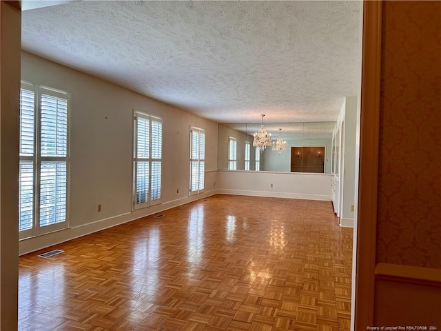 unfurnished living room with parquet floors, a notable chandelier, and a textured ceiling