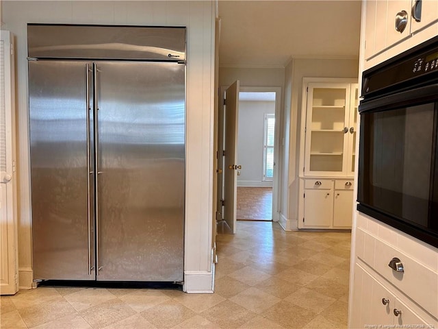 kitchen with crown molding, oven, high end fridge, and white cabinets