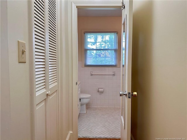 bathroom with tile patterned flooring, tile walls, and toilet