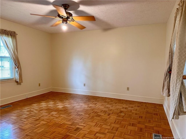 spare room featuring light parquet floors, a textured ceiling, and ceiling fan