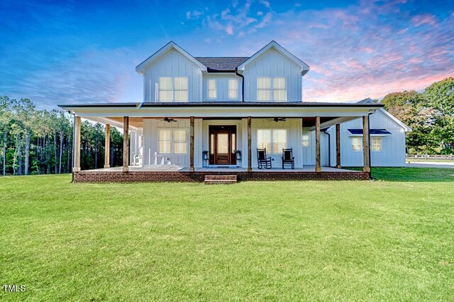 view of front of property featuring a ceiling fan, board and batten siding, covered porch, and a lawn