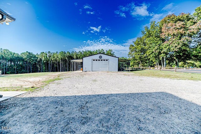 garage featuring driveway, a garage, and fence