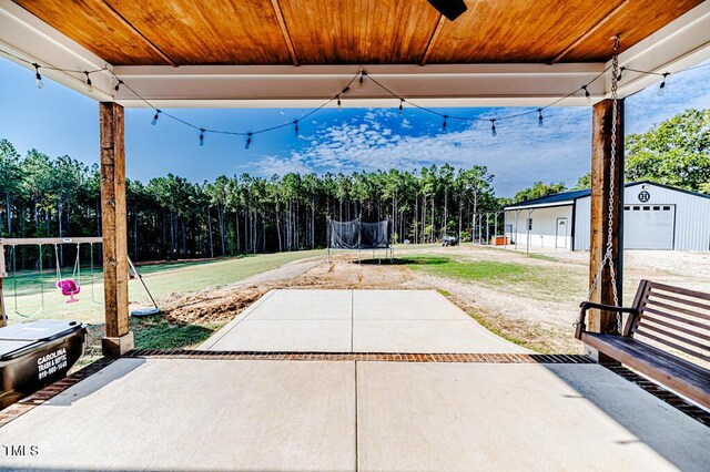 view of patio featuring a trampoline and an outbuilding
