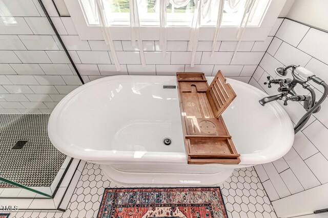 full bath with tile walls, tile patterned flooring, and a bathtub