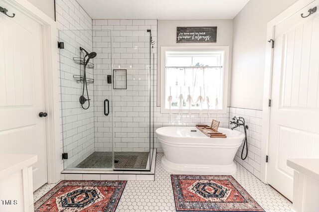 bathroom with tile patterned flooring, a freestanding tub, tile walls, and a shower stall