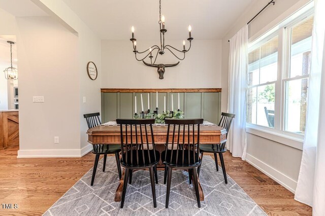 dining room featuring baseboards, a notable chandelier, and light wood-type flooring