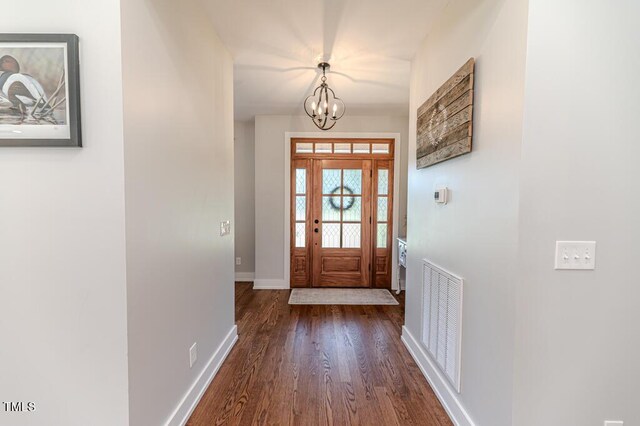 entryway with a notable chandelier, dark wood-type flooring, baseboards, and visible vents
