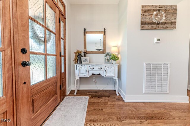entryway featuring wood finished floors, baseboards, and visible vents
