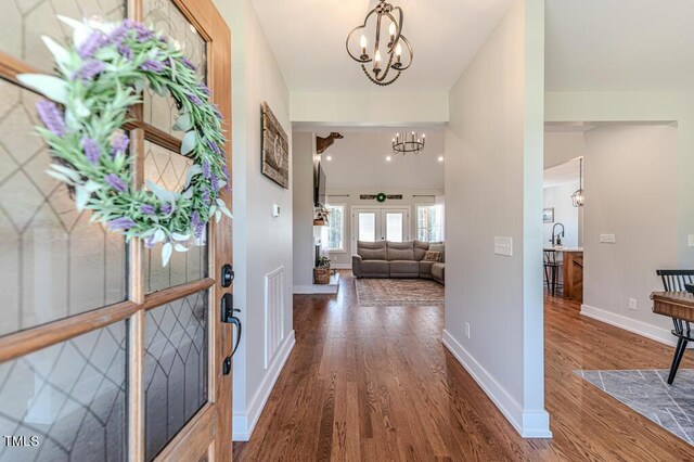 entryway featuring baseboards, visible vents, wood finished floors, and an inviting chandelier