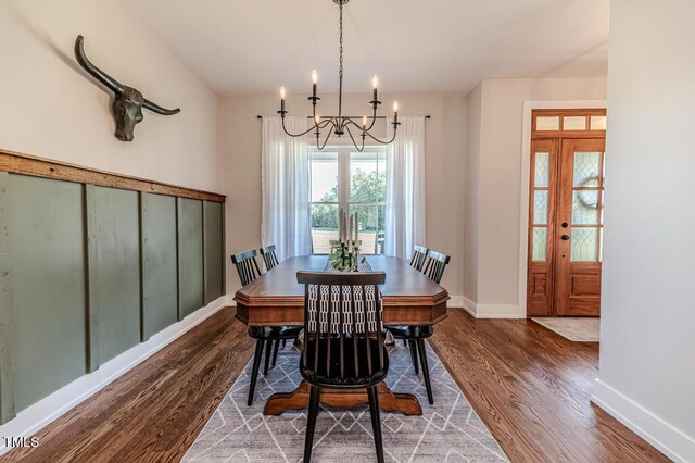 dining space featuring baseboards, wood finished floors, and an inviting chandelier