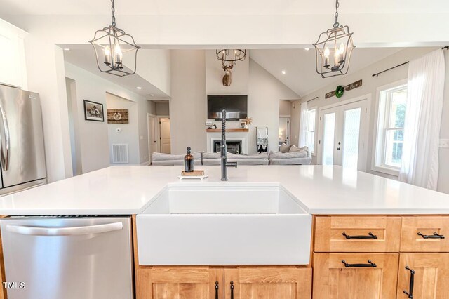 kitchen with a sink, a chandelier, appliances with stainless steel finishes, open floor plan, and visible vents