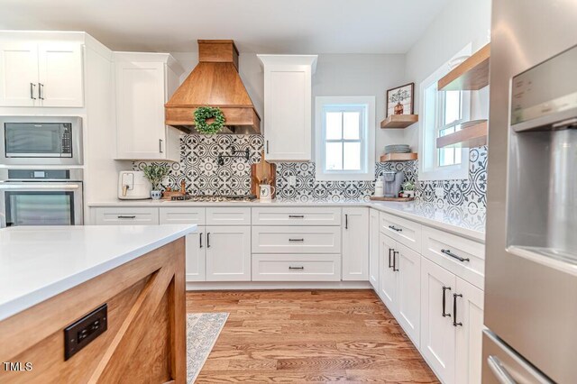kitchen featuring light countertops, backsplash, stainless steel appliances, and custom exhaust hood