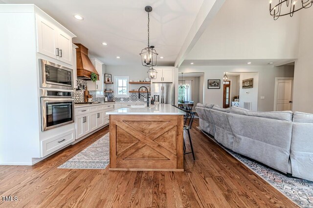 kitchen featuring a chandelier, open floor plan, custom exhaust hood, stainless steel appliances, and dark wood-type flooring