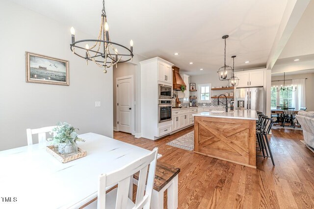 kitchen with light countertops, appliances with stainless steel finishes, a sink, open shelves, and an inviting chandelier