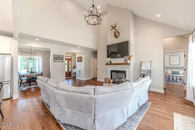 living room with vaulted ceiling, a notable chandelier, wood finished floors, and a fireplace