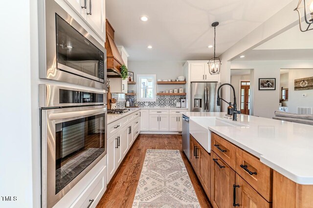 kitchen featuring light countertops, a sink, stainless steel appliances, and open shelves