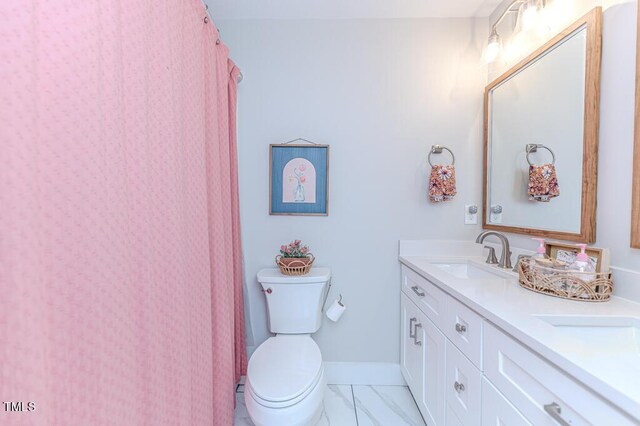 full bath featuring baseboards, marble finish floor, double vanity, toilet, and a sink