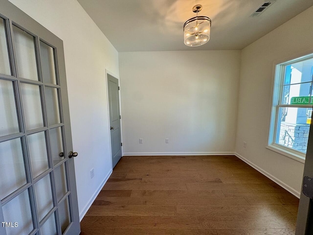 unfurnished room featuring dark wood-style floors, baseboards, and visible vents