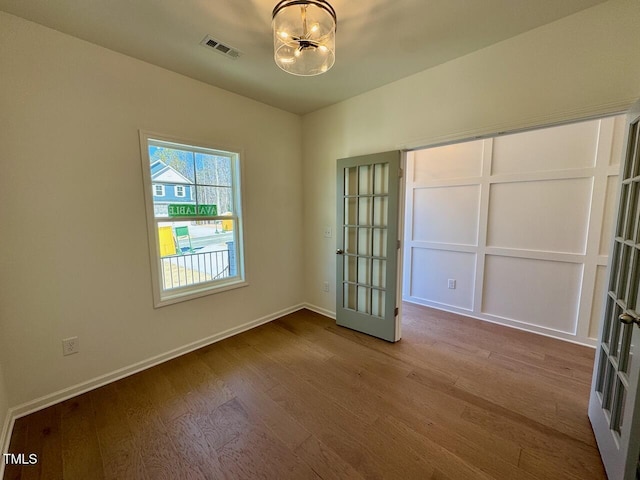 spare room with french doors, visible vents, baseboards, and wood finished floors